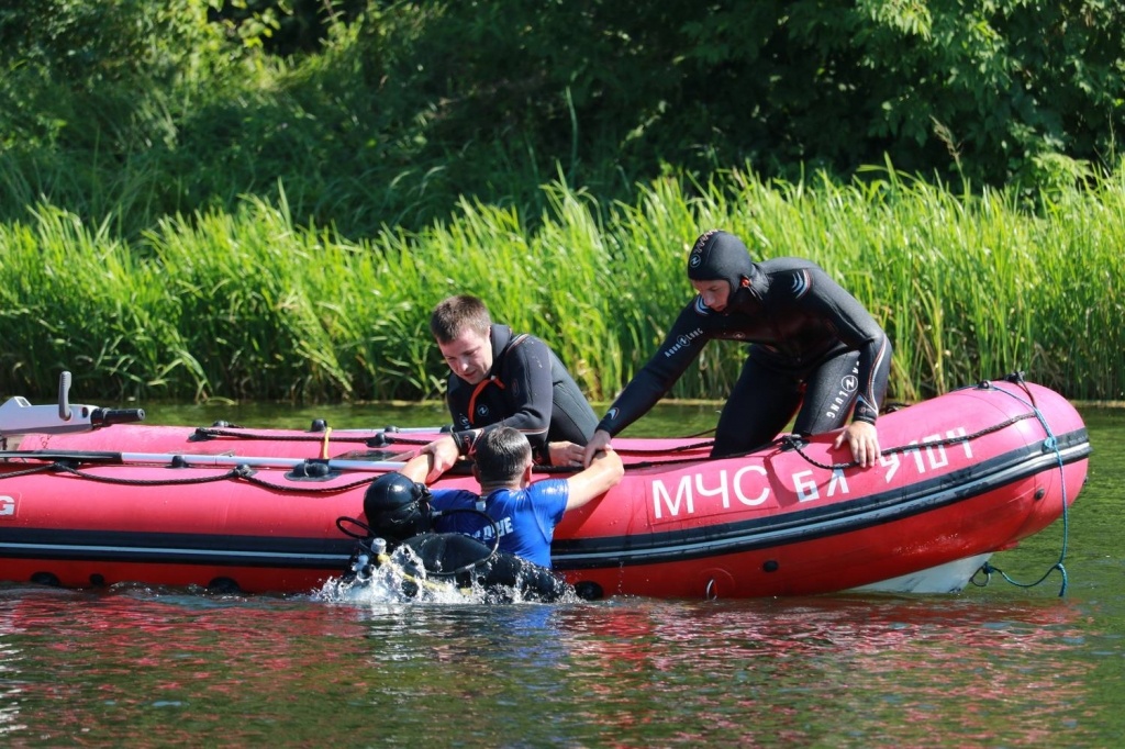 Na zdjęciu widzimy czerwony ponton ratunkowy. W pontonie dwóch ratowników w piankach, w wodzie jeden ratownik trzyma osobę ratowaną.