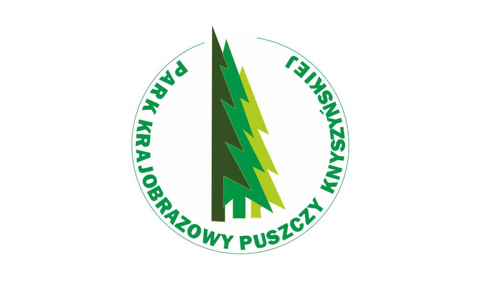 Logo Parku Krajobrazowego Puszczy Knyszyńskiej. Logo jest w kształcie koła z białym tłem. Logo ma zielone drzewa w centrum z napisem “KRAJOWY PARK PUSZCZY KNYSZYŃSKIEJ” napisanym wokół niego. Napis w kololrze zielonym, pisane wielkimi literami.