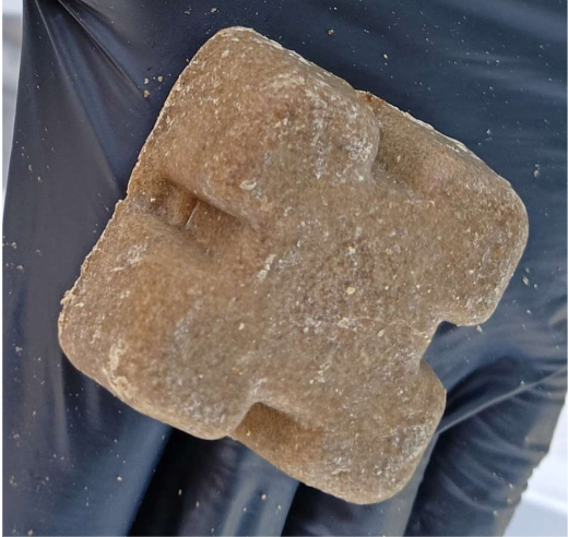 przynęta na lisy o cylindrycznym kształcie z płaskim wierzchołkiem i spodem. Górna powierzchnia zawiera dwie wyżłobione wnęki po przeciwnych stronach, tworząc kształt przypominający krzyż lub znak plusa.